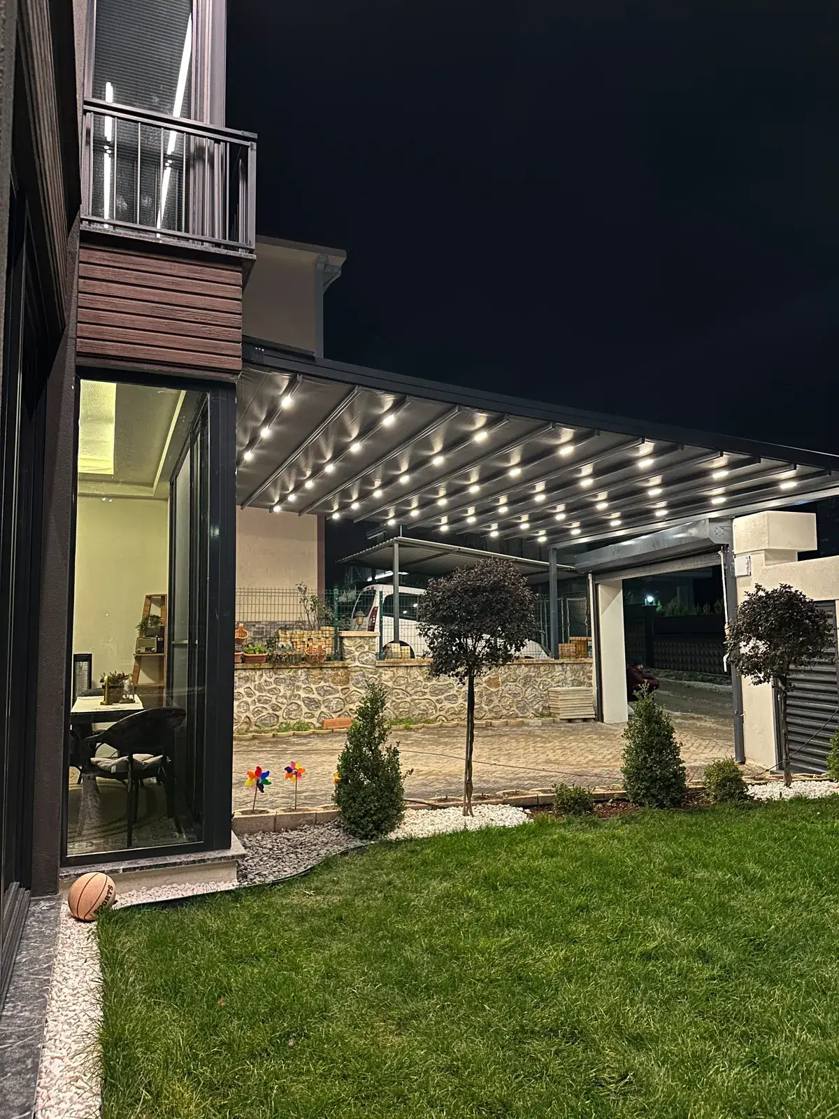 Müstakil ev bahçesinde gece ışıklandırılmış pergola tente