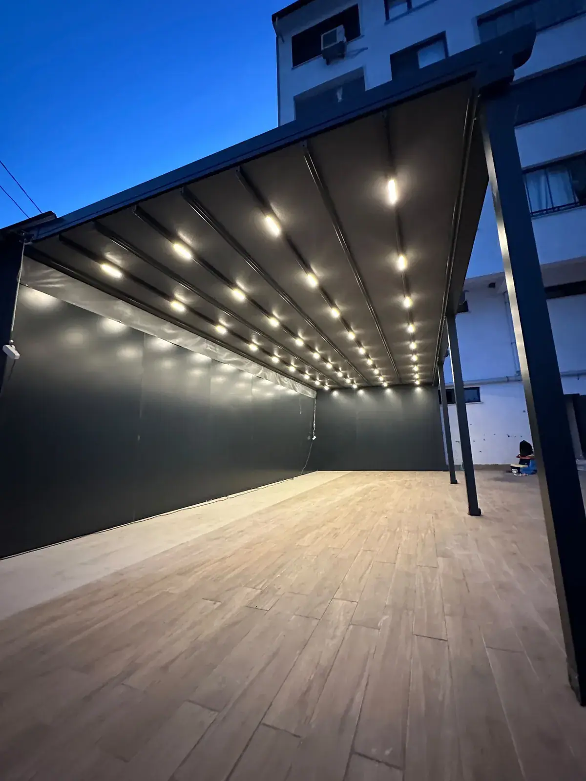 Ahşap zeminli terasta yoğun LED spotlu pergola tente