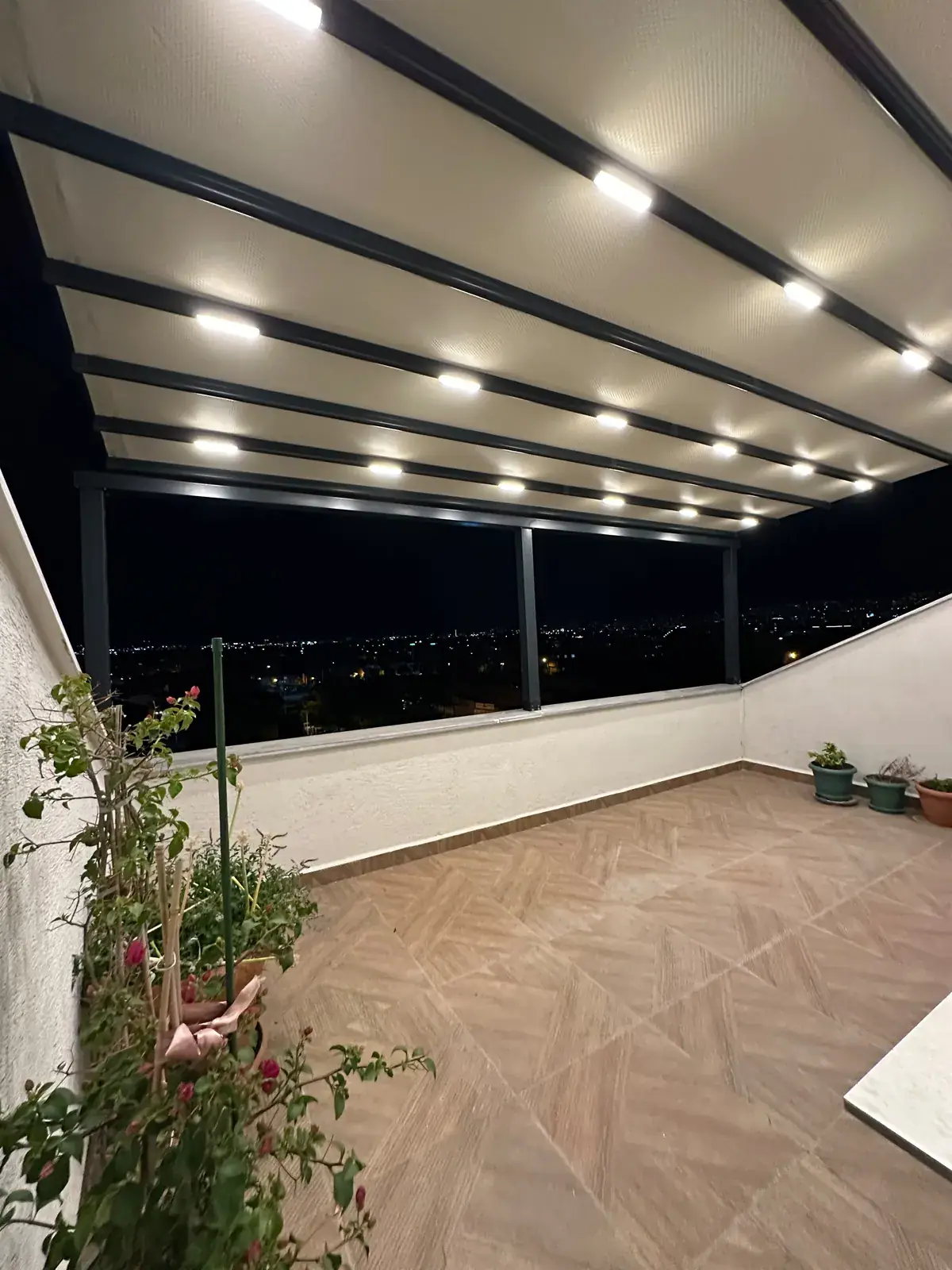 Şehir manzaralı terasta LED aydınlatmalı pergola tente, gece